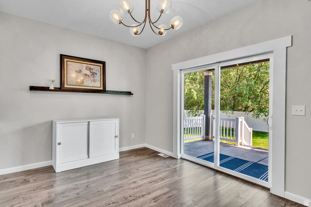 3269 West 650 North Layton, UT 84041 - Photo 12 of 35 Sliding glass patio door with white trim, wood-finish flooring, and a contemporary chandelier
