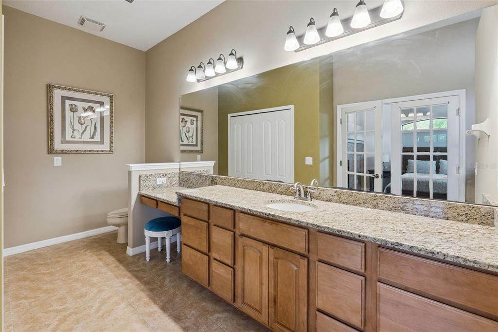 7139 Groveland Farms Road Groveland, FL 34736 - Photo 13 of 36 a bathroom with a granite countertop sink a large mirror and a wooden