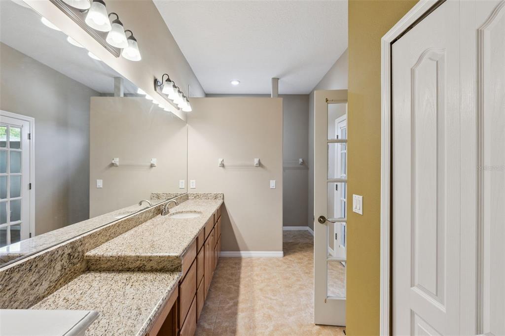 7139 Groveland Farms Road Groveland, FL 34736 - Photo 14 of 36 a spacious bathroom with a granite countertop sink a mirror and a shower