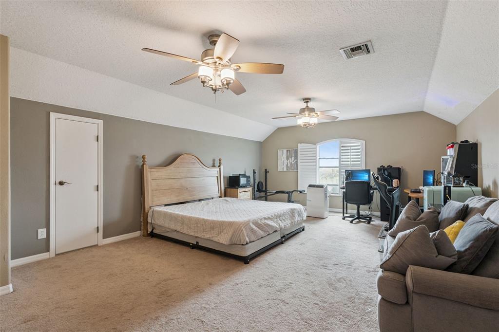 7139 Groveland Farms Road Groveland, FL 34736 - Photo 19 of 36 a spacious bedroom with a bed couch chandelier and a window