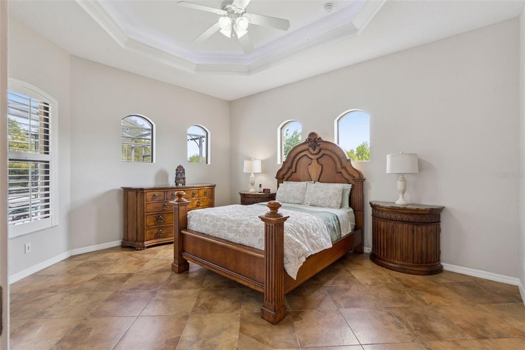 7139 Groveland Farms Road Groveland, FL 34736 - Photo 23 of 36 a spacious bedroom with a bed and a chandelier