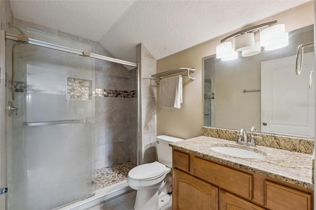7139 Groveland Farms Road Groveland, FL 34736 - Photo 24 of 36 a bathroom with a granite countertop sink toilet and shower