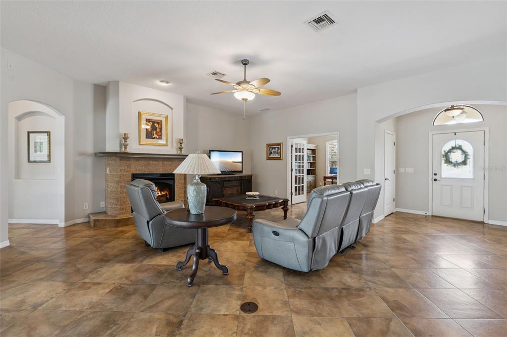 7139 Groveland Farms Road Groveland, FL 34736 - Photo 6 of 36 a living room with furniture a fireplace and a chandelier