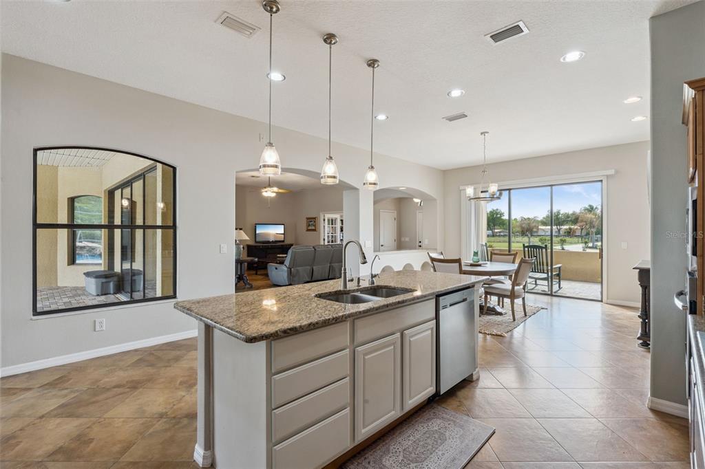 7139 Groveland Farms Road Groveland, FL 34736 - Photo 8 of 36 a kitchen with granite countertop a stove a sink a dining table and chairs
