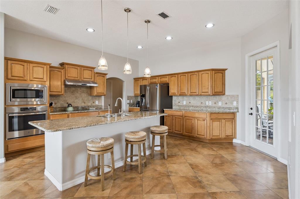 7139 Groveland Farms Road Groveland, FL 34736 - Photo 9 of 36 a large kitchen with a large counter top space a sink stainless steel appliances and cabinets