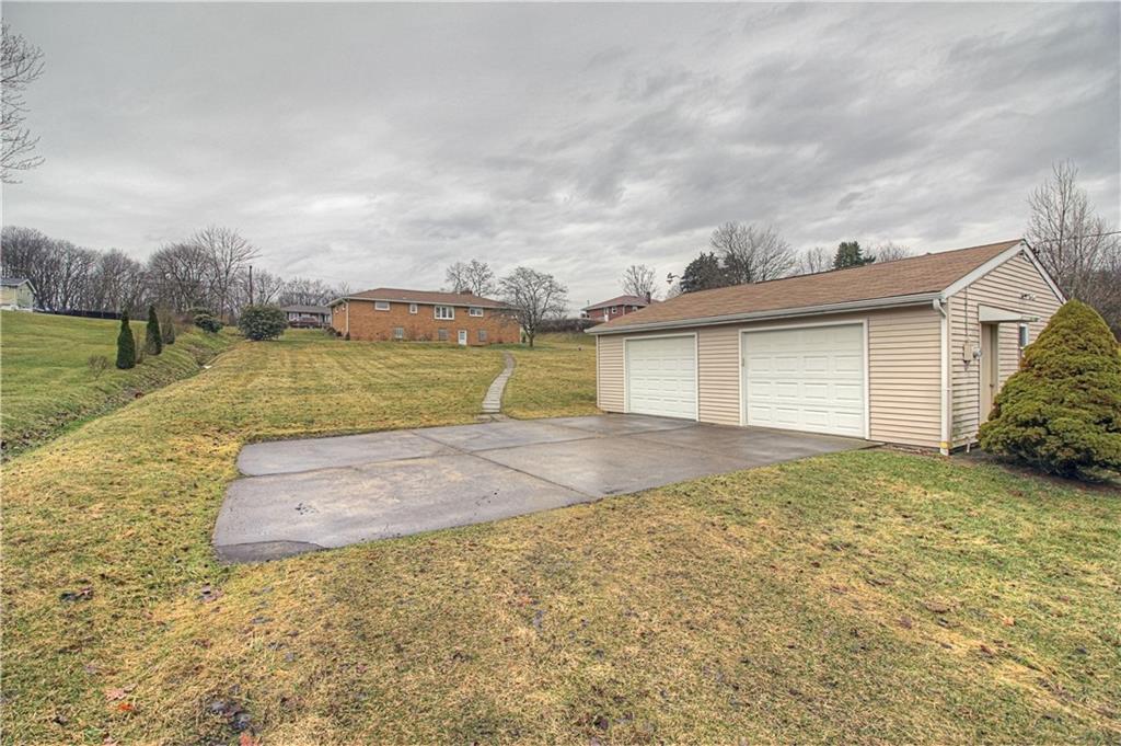 133 Wall Street Rochester, PA 15074 - Photo 22 of 25 Lower lot features a 2+ stall garage wtih man door, concrete parking pad/entry, and a well and septic system. Concrete sidewalk leads to the back door of the house in background.