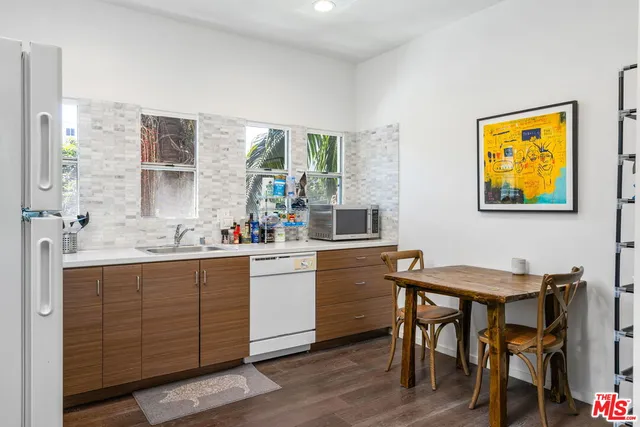 a kitchen with stainless steel appliances kitchen island a table chairs sink and wooden floor