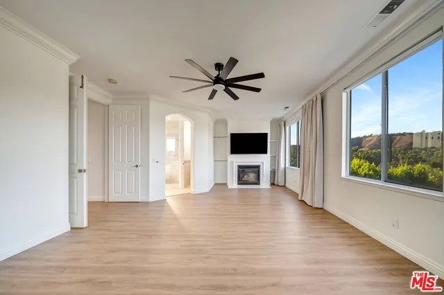 a view of empty room with wooden floor and a ceiling fan