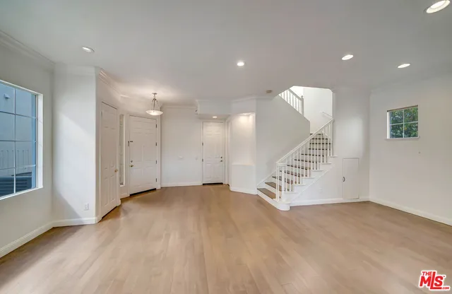 a view of an empty room with wooden floor and stairs