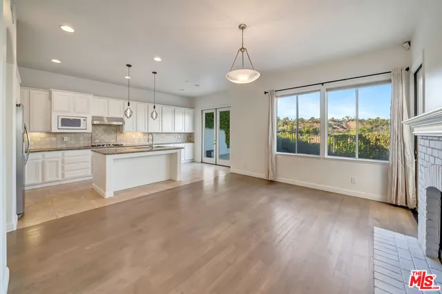 a kitchen with stainless steel appliances granite countertop a stove top oven a sink and white cabinets with wooden floor