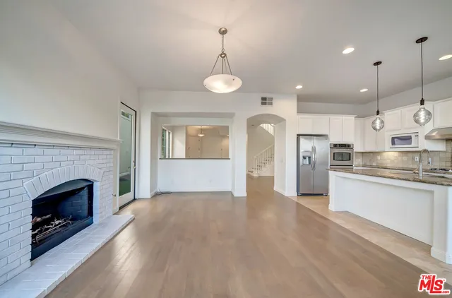 a view of a kitchen with a sink wooden cabinet and a fireplace