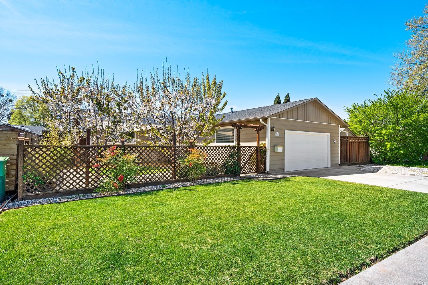a front view of a house with a garden and trees