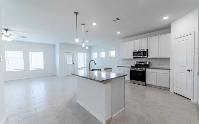 a kitchen with granite countertop white cabinets and stainless steel appliances