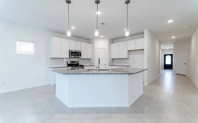 a large kitchen with stainless steel appliances granite countertop a sink a stove and a refrigerator