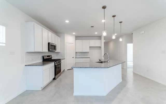 a large white kitchen with kitchen island a sink a stove a oven a dining table and chairs