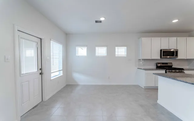 a kitchen with granite countertop white cabinets and stainless steel appliances