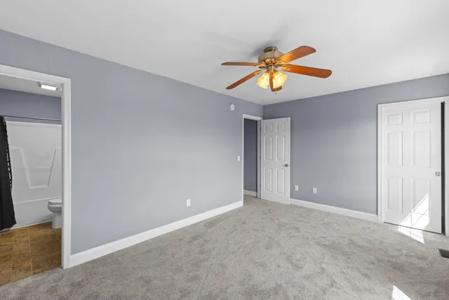 a view of an empty room with window and chandelier fan