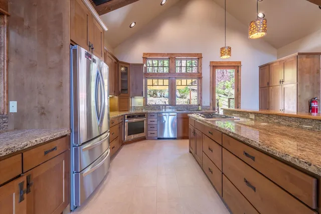 a large kitchen with granite countertop a large counter top stainless steel appliances and windows