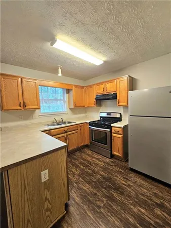 a kitchen with stainless steel appliances a refrigerator a sink a stove top oven and a counter space