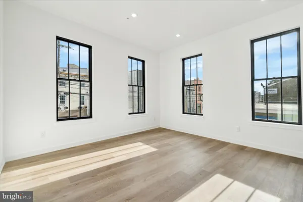 a view of an empty room with wooden floor and windows
