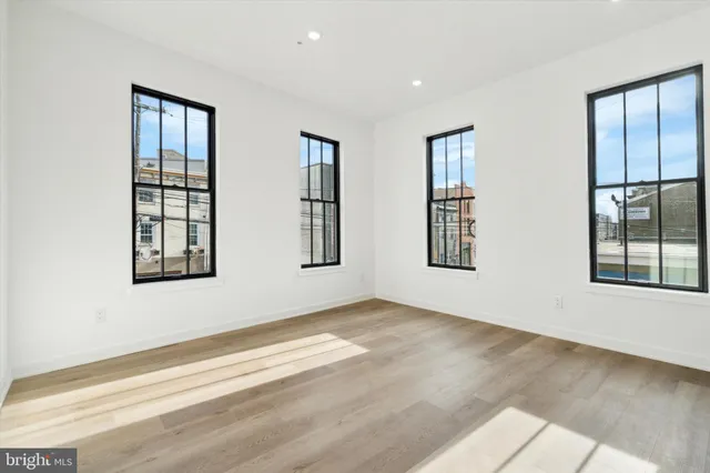 a view of an empty room with wooden floor and windows