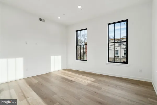 a view of an empty room with wooden floor and windows