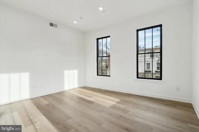 a view of an empty room with wooden floor and windows