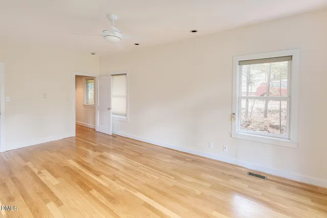 a view of an empty room with a window and a kitchen