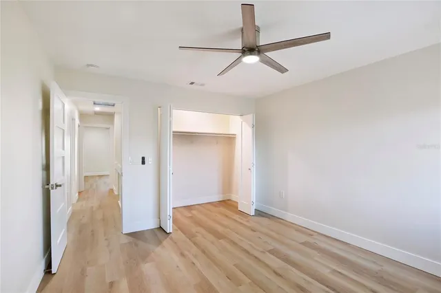 an empty room with wooden floor ceiling fan and windows