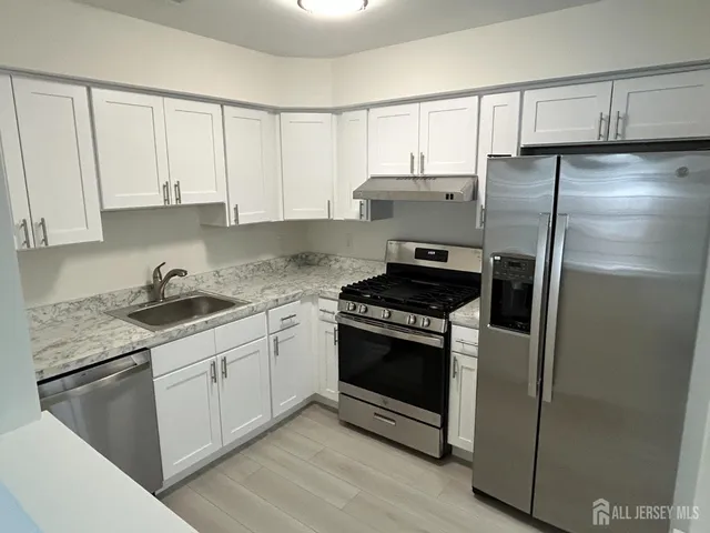 a kitchen with stainless steel appliances granite countertop a stove a refrigerator and a sink with granite countertops