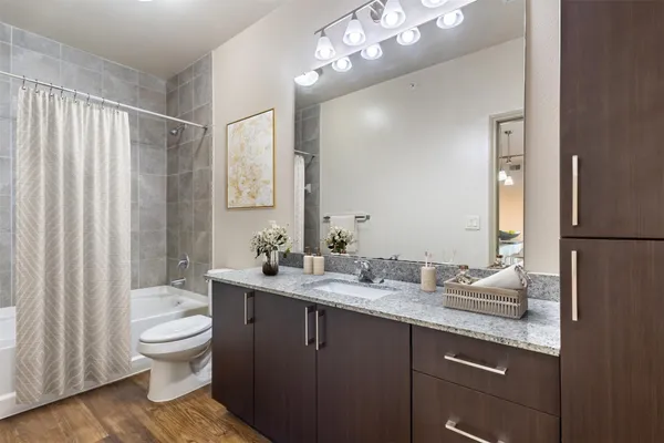 a bathroom with a granite countertop sink toilet a large mirror and shower curtain