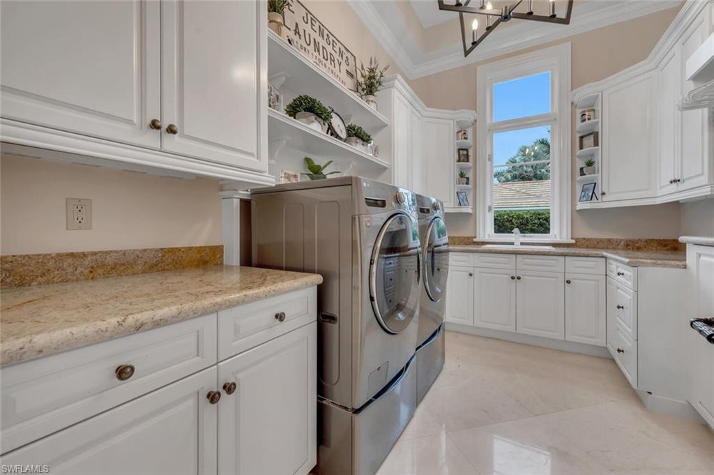 2125 Canna Way Naples, FL 34105 - Photo 33 of 43 Laundry room featuring cabinet space, washing machine and dryer, crown molding, and a chandelier
