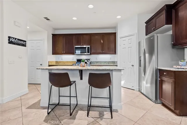 a kitchen with stainless steel appliances kitchen island granite countertop a refrigerator and a stove top oven