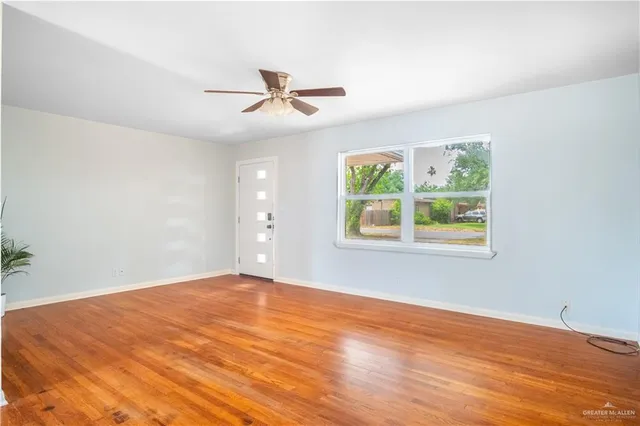 a view of an empty room with window and wooden floor