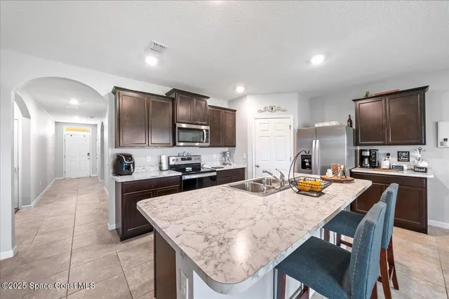 a kitchen with a stove a refrigerator a sink a dining table and chairs with wooden floor