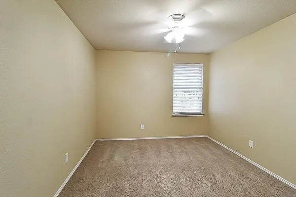 en empty room with a window and a ceiling fan
