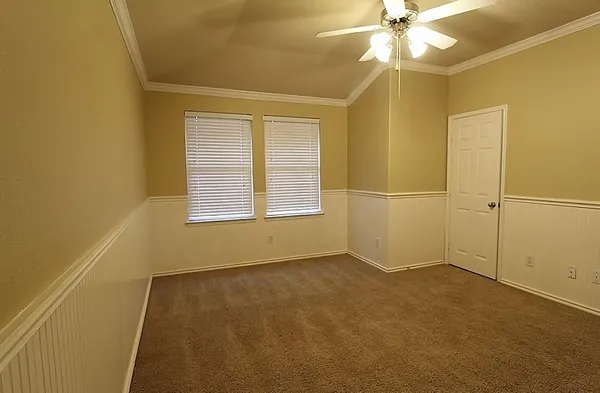 an empty room with a windows and chandelier fan