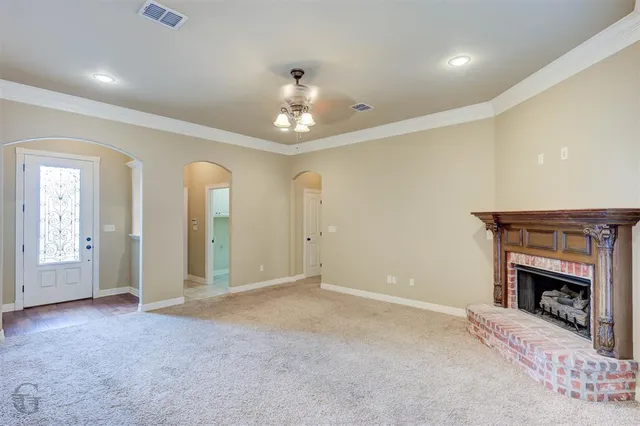 an empty room with chandelier fan and fireplace