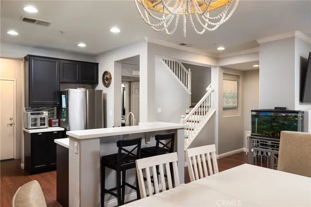 a kitchen with stainless steel appliances kitchen island granite countertop a refrigerator a oven a sink a dining table and chairs