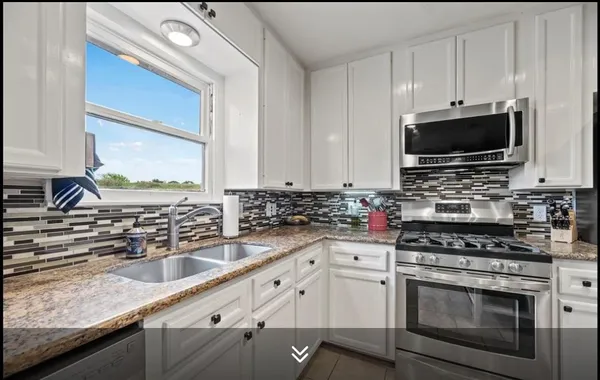 a kitchen with granite countertop a sink stainless steel appliances and cabinets