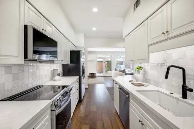 a kitchen with a sink a counter top space stainless steel appliances and cabinets