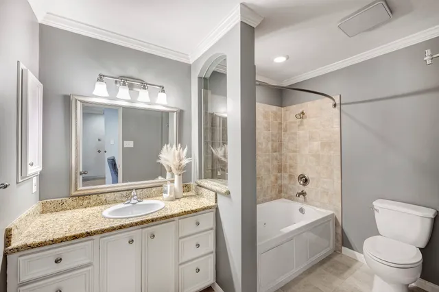 a bathroom with a granite countertop tub sink toilet and mirror