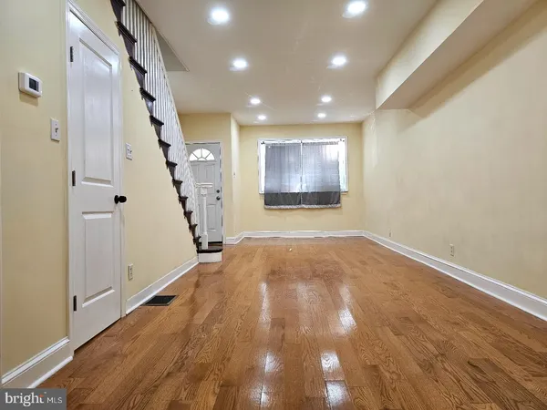 a view of an empty room with wooden floor and stairs