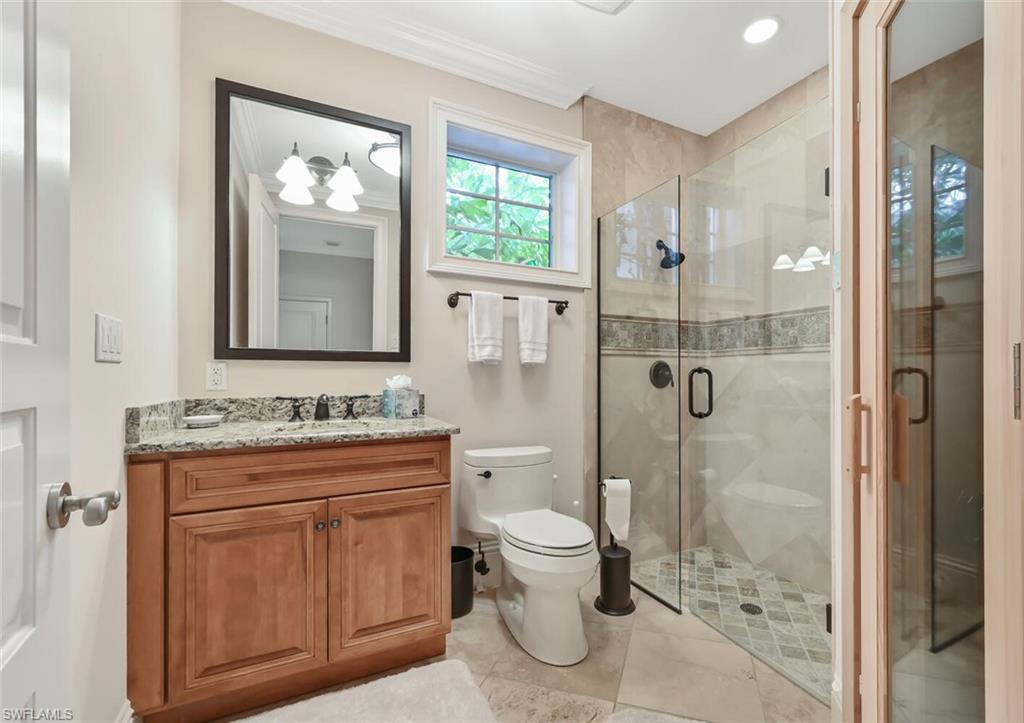 425 5th Street South, Unit A Naples, FL 34102 - Photo 32 of 44 a bathroom with a granite countertop toilet a sink and a mirror