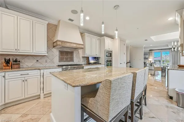 a kitchen with kitchen island granite countertop a stove a sink a oven and a refrigerator with white cabinets