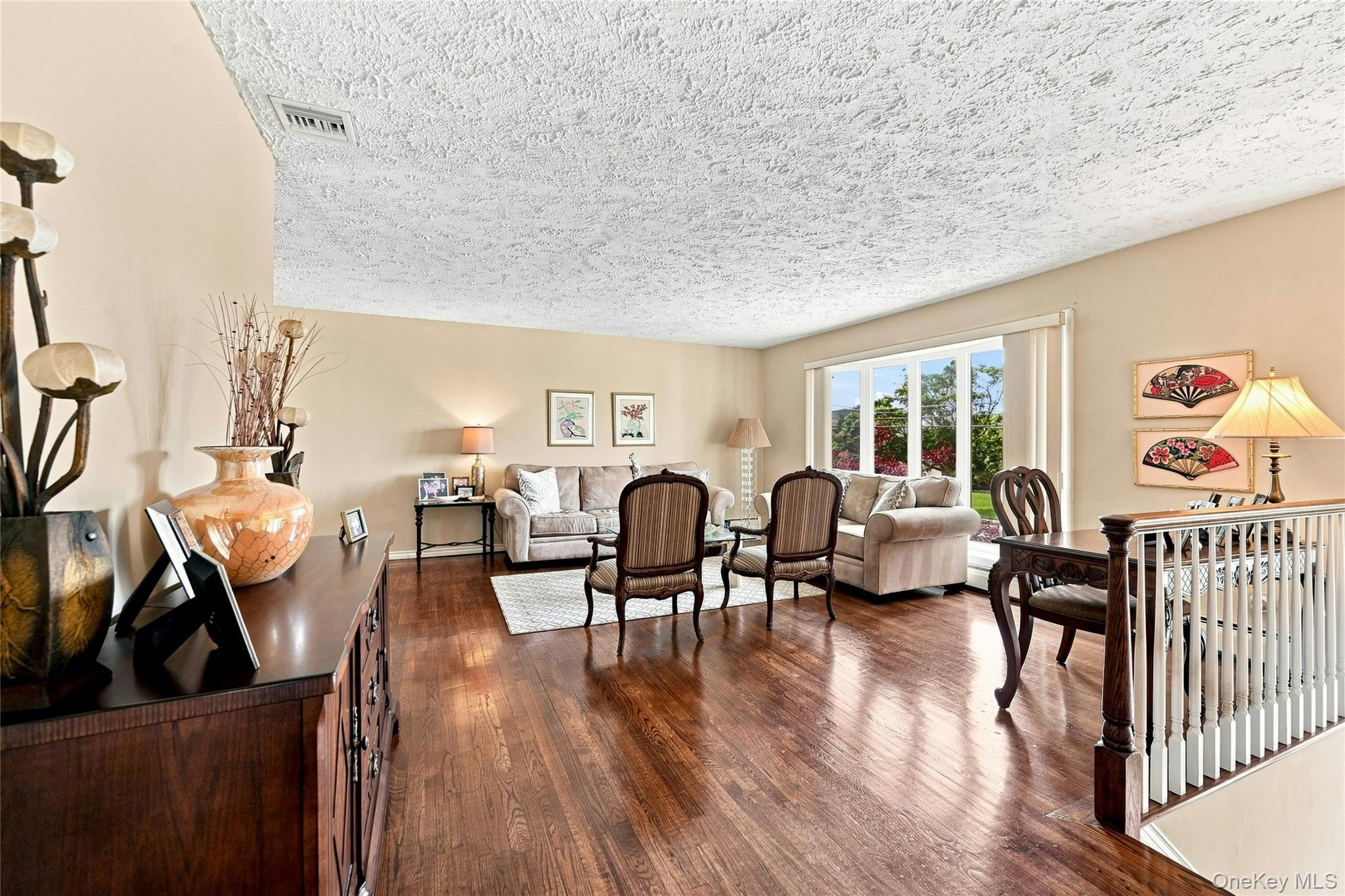 3165 Clubhouse Road Merrick, NY 11566 - Photo 12 of 45 Expansive living room featuring rich hardwood flooring, a bow window bringing ample natural light to the space