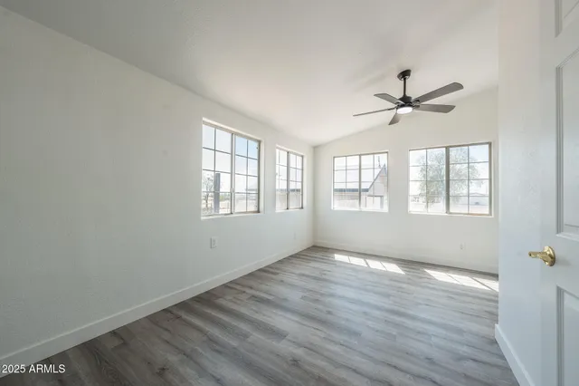 a view of an empty room with a window and wooden floor