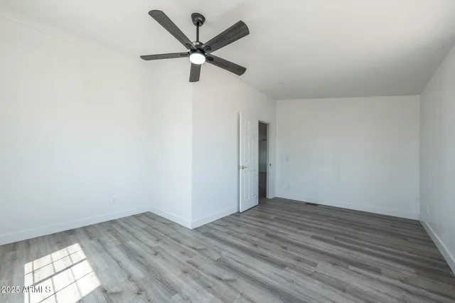 an empty room with wooden floor and a ceiling fan