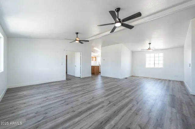 a view of an empty room with a window and wooden floor