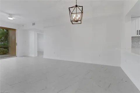 en empty room with windows and chandelier fan